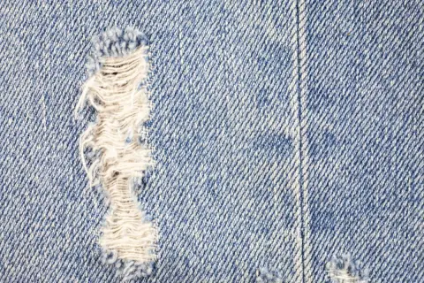 Zbliżenie na niebieski denim z przetarciami. Dowiedz się, jak zrobic przetarcia na dzinsach, by nadać im stylowy, znoszony wygląd.