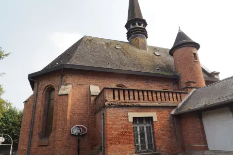 L'église en briques rouges de Saint-Venant, avec son clocher pointu et sa tourelle, semble prête pour un match de basket.