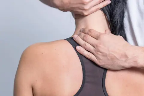 Hände massieren seitlich den Nacken, um Verspannungen im Hals zu lösen.