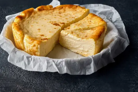 Un délicieux fiadone, recette corse, est servi sur du papier sulfurisé. Sa croûte dorée et sa texture crémeuse invitent à la dégustation.
