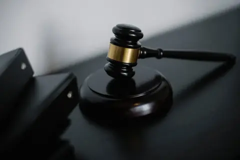 Młotek sędziowski i akta sądowe. Dowiedz się, jak uzyskać protokół z rozprawy sądowej.
