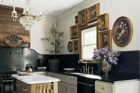 A luxurious kitchen with a crystal chandelier, ornate wood paneling, and a collection of framed floral paintings, evoking the grandeur of Victorian houses.