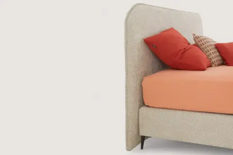 Lit moderne avec tête de lit capitonnée, drap orange vif et coussins rouges. Idées pour comment fixer tête de lit.