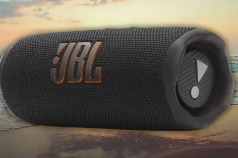 Enceinte JBL noire sur une plage. Découvrez comment fonctionne une enceinte JBL pour une expérience sonore immersive, même en extérieur.
