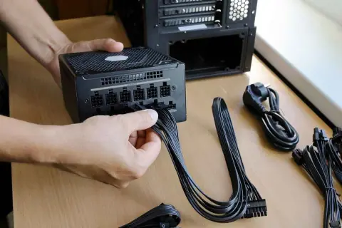 Persona conecta cables a una fuente de alimentación de PC. Es el momento de comprobar fuente de alimentación pc.