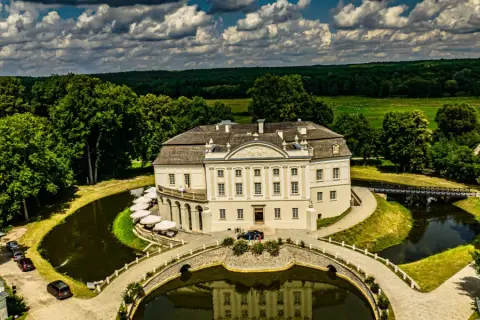 Pałac w Kurozwękach, otoczony fosą i parkiem, to wspaniałe atrakcje. Widać mostki, stawy i otaczający las.