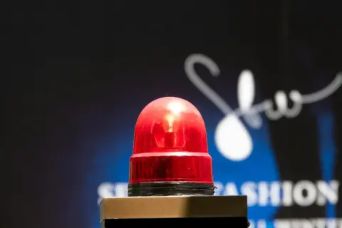 Une sirène rouge clignote, comme son alarme maison, sur un fond sombre avec un logo blanc stylisé.