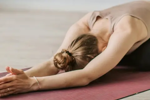 Une femme en posture de yoga, bras tendus, sur un tapis. Un moment pour apprendre comment s'apaiser.