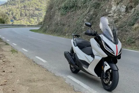 Scooter Zontes blanca en carretera sinuosa. Opiniones sobre motos Zontes: diseño moderno y ágil para rutas de montaña.