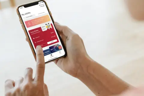 Osoba korzysta z aplikacji Airalo na telefonie, pokazując, jak działa usługa eSIM. Widoczne są aktywne pakiety danych i opcja doładowania.