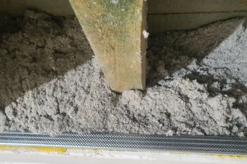 Izolacja z celulozy, która to ekologiczny materiał, wypełnia przestrzeń między drewnianymi belkami stropowymi.