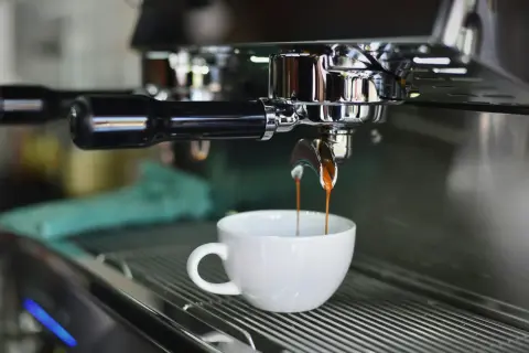 Macchina da caffè professionale eroga un espresso in tazza bianca. Il consumo di una macchina del caffè da bar varia, ma questa è un'immagine iconica.