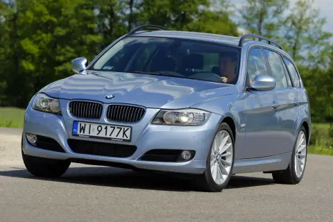 Błękitne BMW E91 na drodze, widać wyraźnie jego przednie światła i grill.