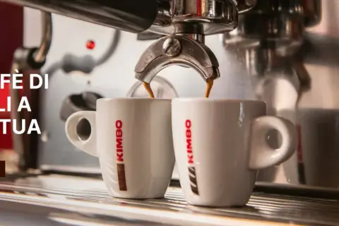 Två vita kaffekoppar fylls med italienskt kaffe från en espressomaskin.