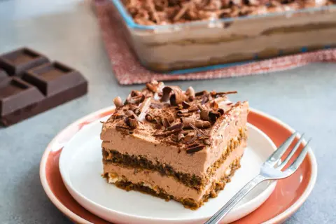 Una fetta di goloso tiramisù al cioccolato e mascarpone, guarnito con riccioli di cioccolato fondente.