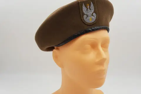 Brązowy beret wojskowy z orłem, jeden z rodzajów czapek wojskowych, prezentowany na manekinie.