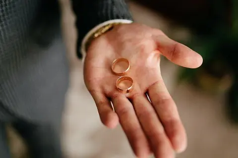 Dos anillos de oro descansan en una mano abierta, listos para ajustar el anillo y sellar un compromiso.
