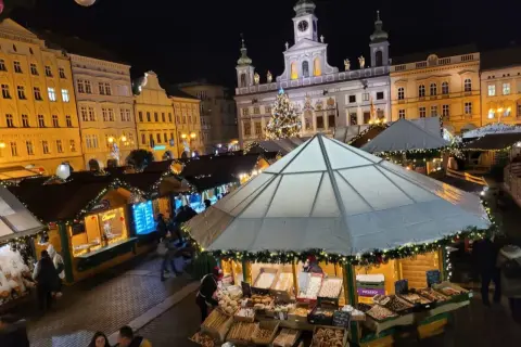 Festlicher budweis weihnachtsmarkt mit beleuchteten Buden, einem Weihnachtsbaum und historischen Gebäuden im Hintergrund.