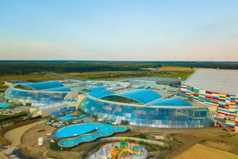 Nowoczesny kompleks z basenami i zjeżdżalniami, największy park wodny w Polsce, otoczony zielenią.