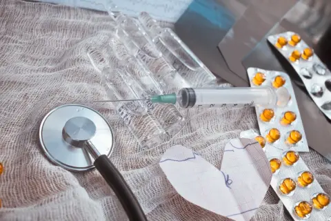 Stetoskop, ampułki, strzykawka i tabletki na liście leki przeciwzakrzepowe. Serce z EKG.