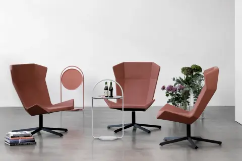 Tre moderna fåtöljer från Johanson Design i terrakottafärgad klädsel, placerade i ett stilrent rum med en sidobänk och blommor.