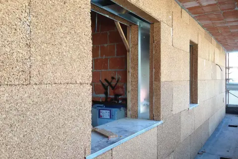 Blocchi di sughero, il miglior isolante termico naturale, rivestono le pareti di un edificio in costruzione, con aperture per finestre.