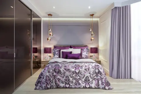 Elegancka, fioletowa sypialnia z bogato zdobioną pościelą, lustrzaną szafą i nowoczesnymi lampami.
