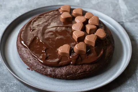 En saftig fransk chokladtårta täckt med chokladglasyr och dekorerad med små chokladhjärtan.