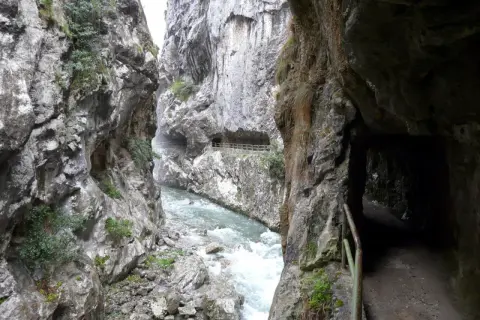 Sendero tallado en roca junto a un río caudaloso, parte de la ruta cain.
