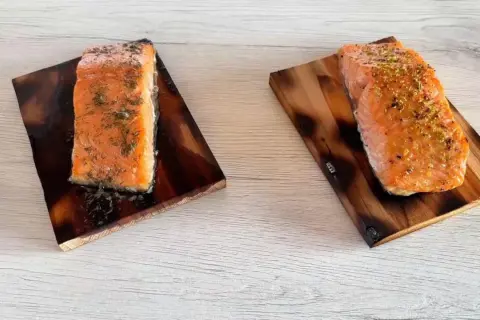 Due tranci di salmone, uno condito con aneto e l'altro con scorza di limone, pronti per essere gustati.