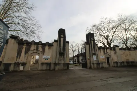 Entrée imposante du cimetière du Sud à Nancy, avec ses piliers de pierre patinés par le temps et ses grilles ouvragées.