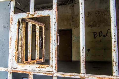Grille rouillée d'une cellule abandonnée, porte ouverte. Un vestige de l'urbex à Laval, où le passé murmure.