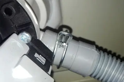 Dettaglio del tubo di scarico della lavatrice, fissato con fascetta metallica. Utile per capire come pulire il tubo di scarico della lavatrice.