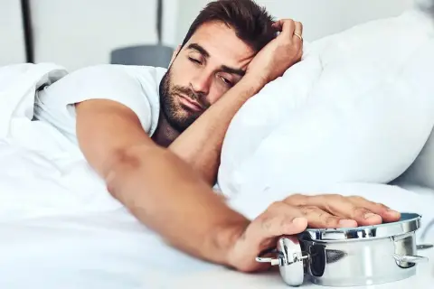 Man struggling to wake up, embodying the dysania meaning of difficulty getting out of bed.