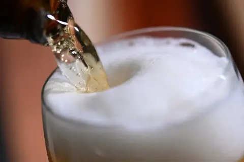 Piwo nalewane do szklanki. Czy piwo pomaga na kamienie nerkowe? Piana tworzy się na powierzchni.