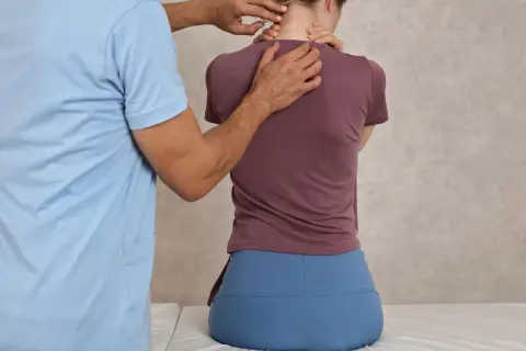 Fizjoterapeuta bada plecy pacjentki, która może mieć hiperlordozę.
