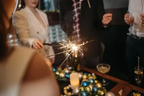 Ludzie trzymają zimne ognie, świętując Nowy Rok. Pamiętaj, czego nie robic w nowy rok, by zabawa była bezpieczna.