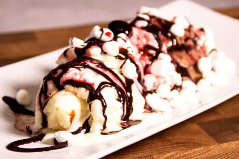 En läcker banana split med tre kulor glass, chokladsås, marshmallows och körsbär.