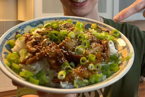 Leckeres Hähnchen Teriyaki Rezept: saftiges Hähnchen in Teriyaki-Sauce auf Reis, garniert mit Frühlingszwiebeln und Sesam.