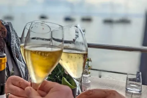 Sektgläser stoßen an, mit Blick auf den Bodensee. Ein schöner Moment, vielleicht nach einem Besuch beim Winzerverein Hagnau.