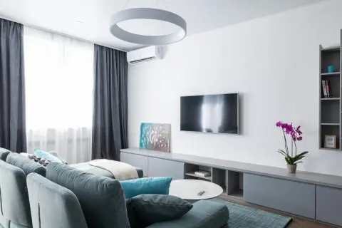 Nowoczesny salon z kanapą, telewizorem i klimatyzacją. Zastanawiasz się, ile kosztuje montaż klimatyzacji?