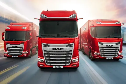 Trois camions DAF rouges sur une route floue. L'intérieur du DAF XF est visible, avec un conducteur au volant.