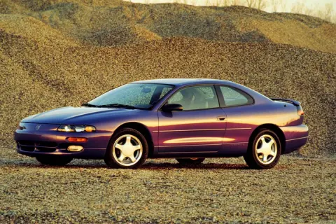 Fioletowy Dodge Avenger z lat 90. stoi na tle żwirowych wzgórz.