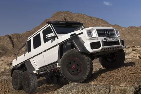Biały Mercedes G63 AMG 6x6 z sześcioma kołami na skalistym pustynnym terenie.
