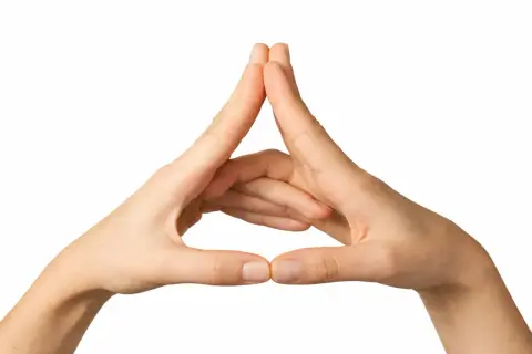 Manos formando un triángulo, un gesto de mudras de protección para invocar seguridad y equilibrio.