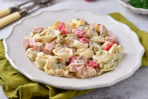 Prosta sałatka z tortellini, szynką, pomidorkami i ogórkiem konserwowym, polana kremowym sosem.