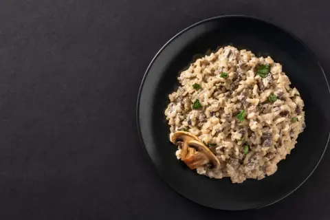 Un crémeux risotto aux champignons, garni de persil frais et d'une tranche de champignon. Un délice végétarien.