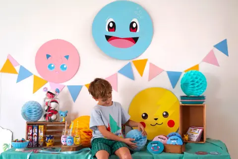 Décoration Pokémon à faire soi-même pour une fête : Pikachu, Rondoudou et Carapuce souriants, guirlandes colorées et un garçon émerveillé.