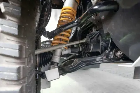 Detailaufnahme der Radaufhängung eines Fahrzeugs. Ein defekter Querlenker kann sich durch Geräusche und schlechtes Fahrverhalten bemerkbar machen.