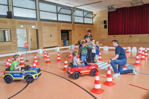 Kinder lernen spielerisch Verkehrsregeln bei der Verkehrserziehung im Kindergarten. Kleine Autos und Pylonen simulieren eine Straße.